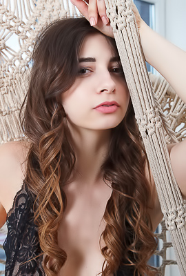 Elle Mira poses topless in black lace lingerie on a hanging chair by the bedroom window